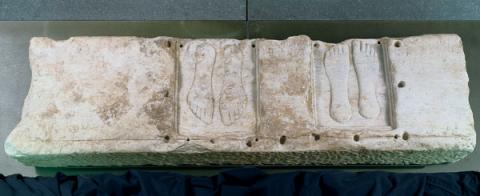 Lastra con due coppie di piedi a rilievo e iscrizione con dedica alla dea Caelestis Lastra con due coppie di piedi a rilievo e iscrizione con dedica alla dea Caelestis